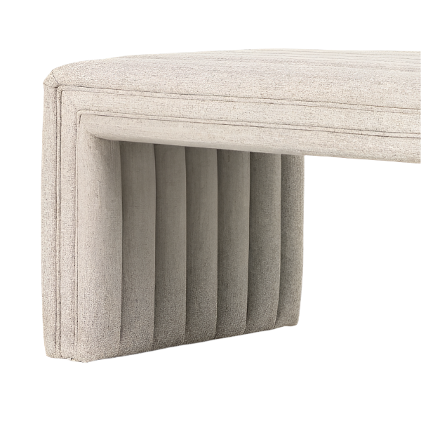 Close-up of an upholstered end-of-bed bench corner in natural beige boucle fabric, showing the padded seat with stitched border and vertical channel-tufted bench leg.