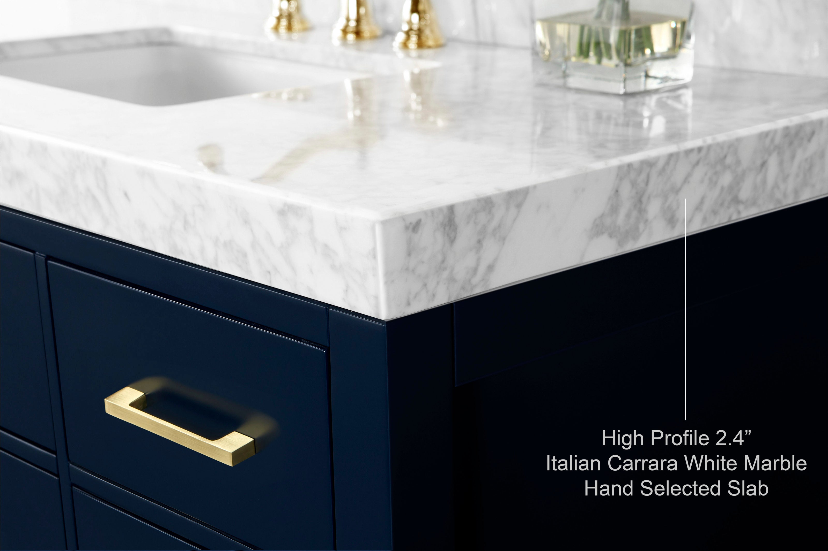 Close-up of a modern solid wood bathroom vanity corner showing a 2.4" Italian Carrara white marble stone top with gray veining, dark navy wood cabinet face and brushed gold drawer handle with sink cutout.