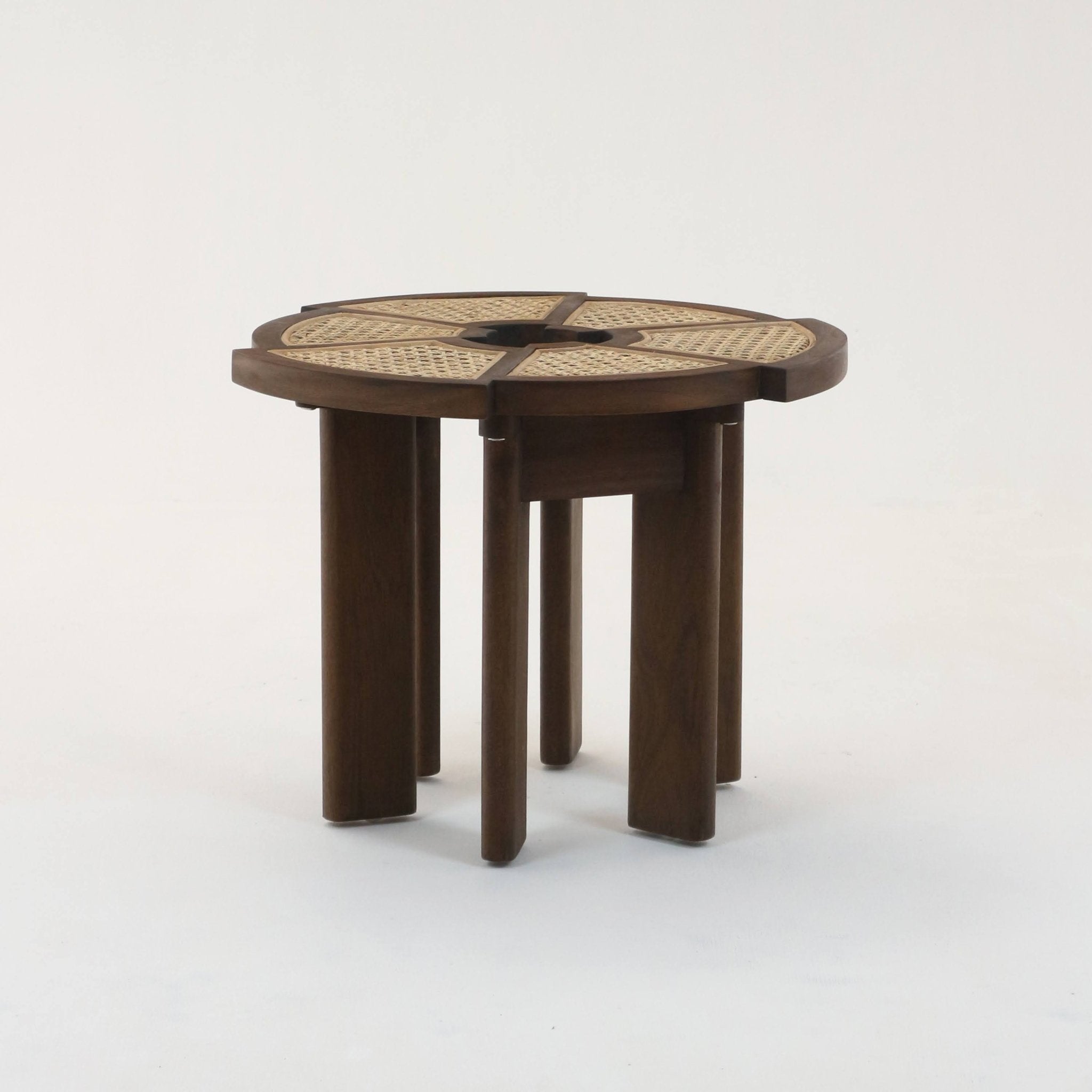 Round teak side table with medium-brown solid wood frame, four radial woven cane panels and a central circular cutout, supported by grouped rounded legs for a modern mid-century look.