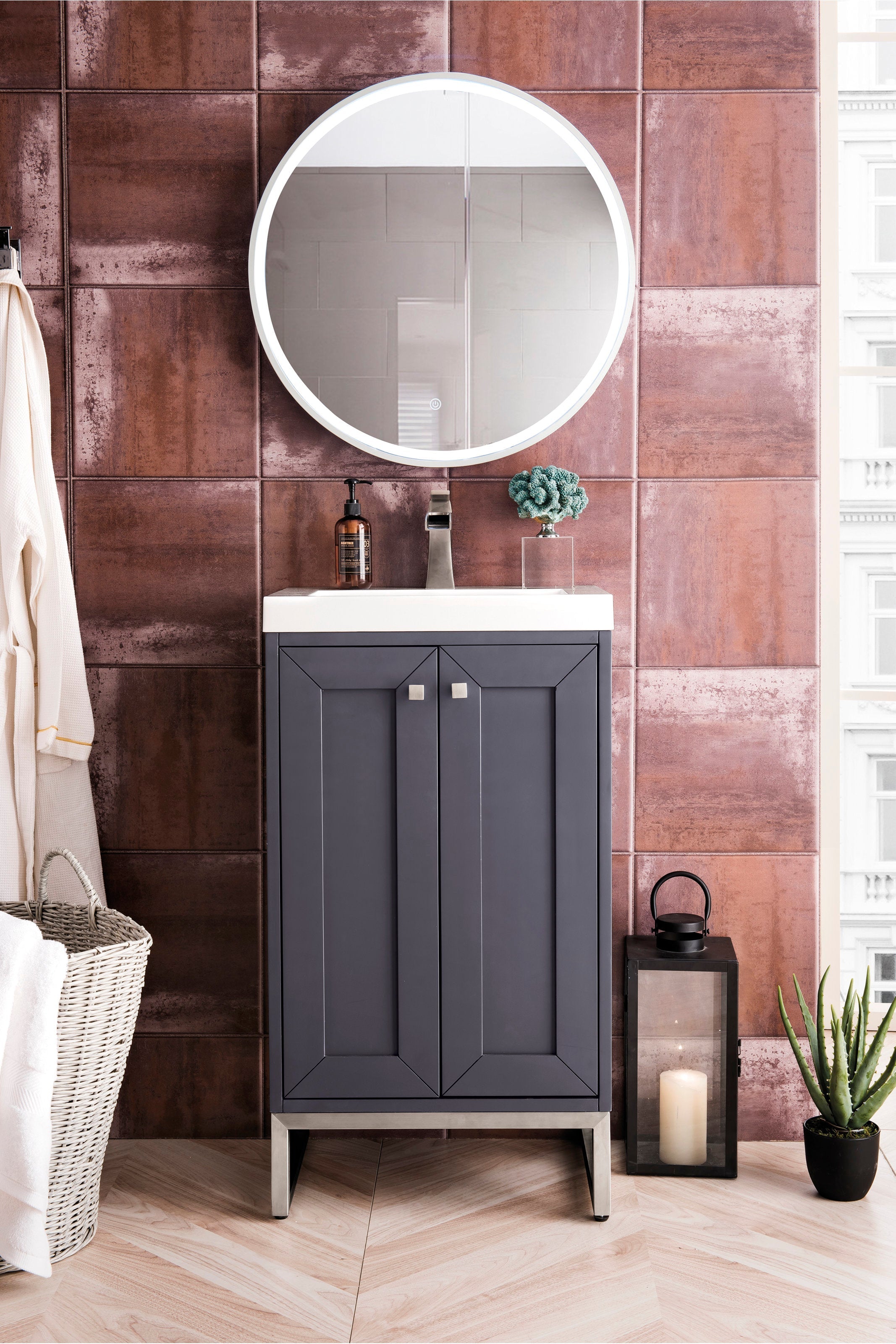 Freestanding modern solid-wood bathroom vanity with a stone top and integrated ceramic single sink, dark gray paneled doors, brushed nickel legs and square knobs, shown with round LED mirror and terracotta tile wall.