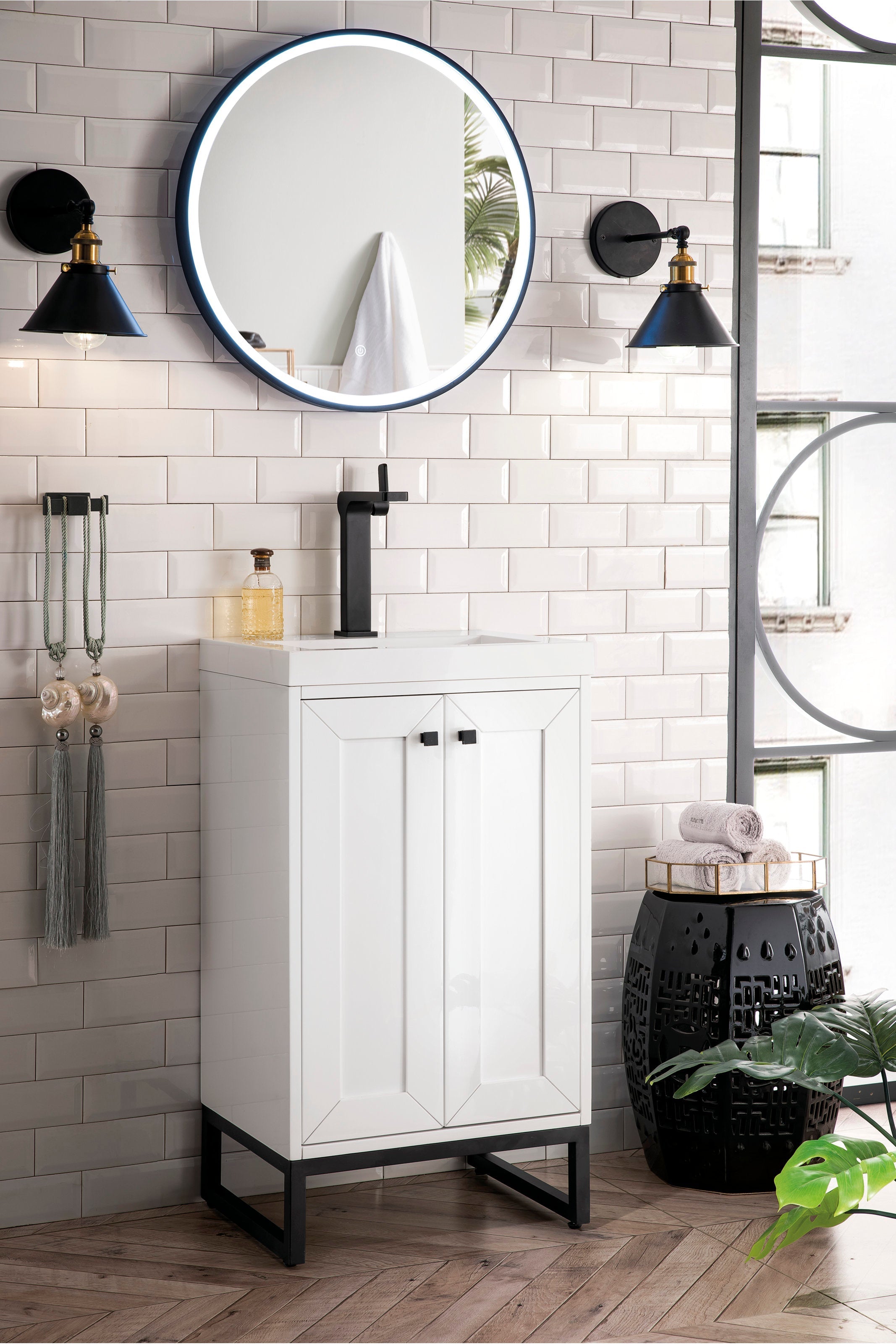 Freestanding modern solid wood single-sink vanity with a stone top and white cabinet, black single-handle faucet and black metal base, shown under a round LED mirror on glossy subway tile.