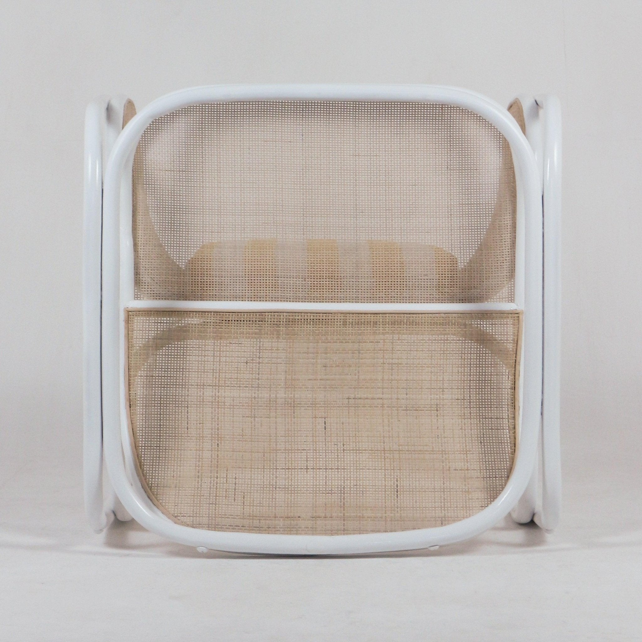 Front view of a modern white metal-framed lounge chair with natural cane back and seat and a beige striped seat cushion.