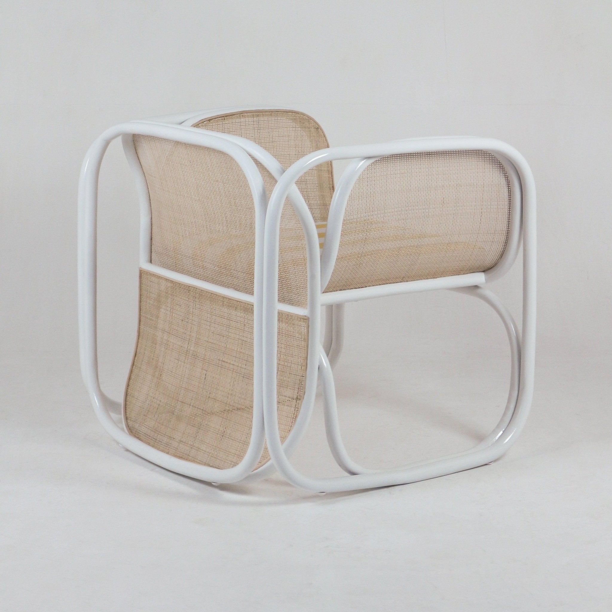 Modern lounge chair with curved white tubular metal frame and natural woven cane seat and back, low-profile contemporary silhouette suitable for living rooms.