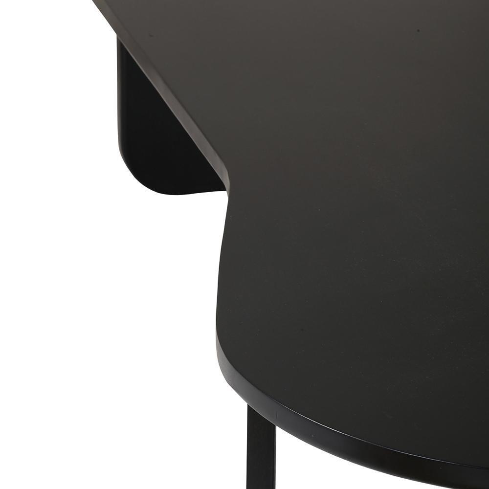 Close-up of a black solid wood modern coffee table top showing a rounded edge, inset lower shelf and a slender leg, highlighting the smooth matte finish and minimalist contemporary profile.