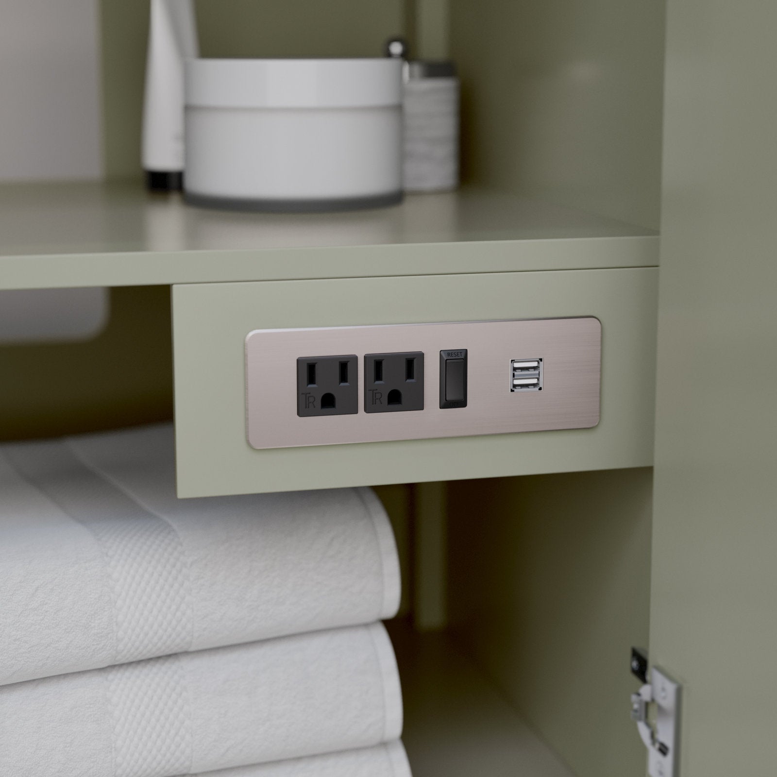 Close-up of a stone-colored solid wood bathroom vanity interior showing a brushed-metal power plate with two electrical outlets, a reset switch and dual USB ports mounted above neatly folded white towels.