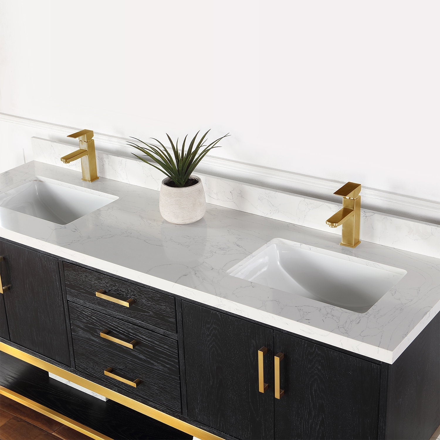 Modern solid wood double-sink bathroom vanity with a stone-look white marble countertop, two rectangular undermount ceramic sinks, brushed gold faucets and matching hardware, and a small potted plant on the counter.