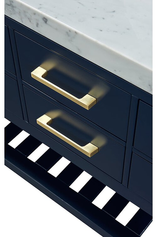 Close-up of a modern solid wood bathroom vanity showing a white stone countertop, deep navy painted drawers, brushed gold/brass rectangular drawer pulls and a slatted open bottom shelf.