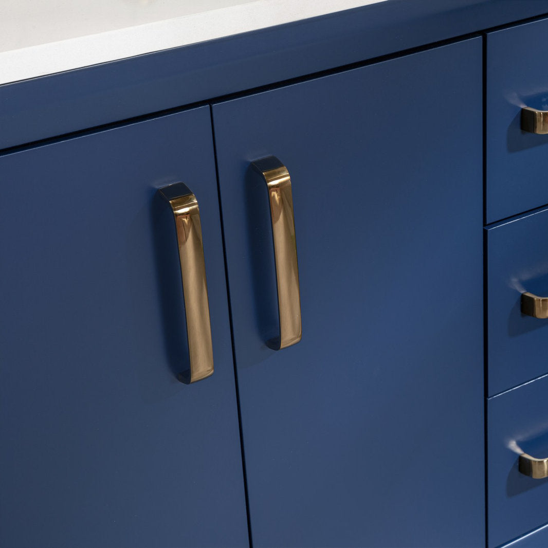 Close-up of a modern navy solid wood vanity with a white stone top, showing polished brass cabinet handles on the center doors and adjacent drawers.