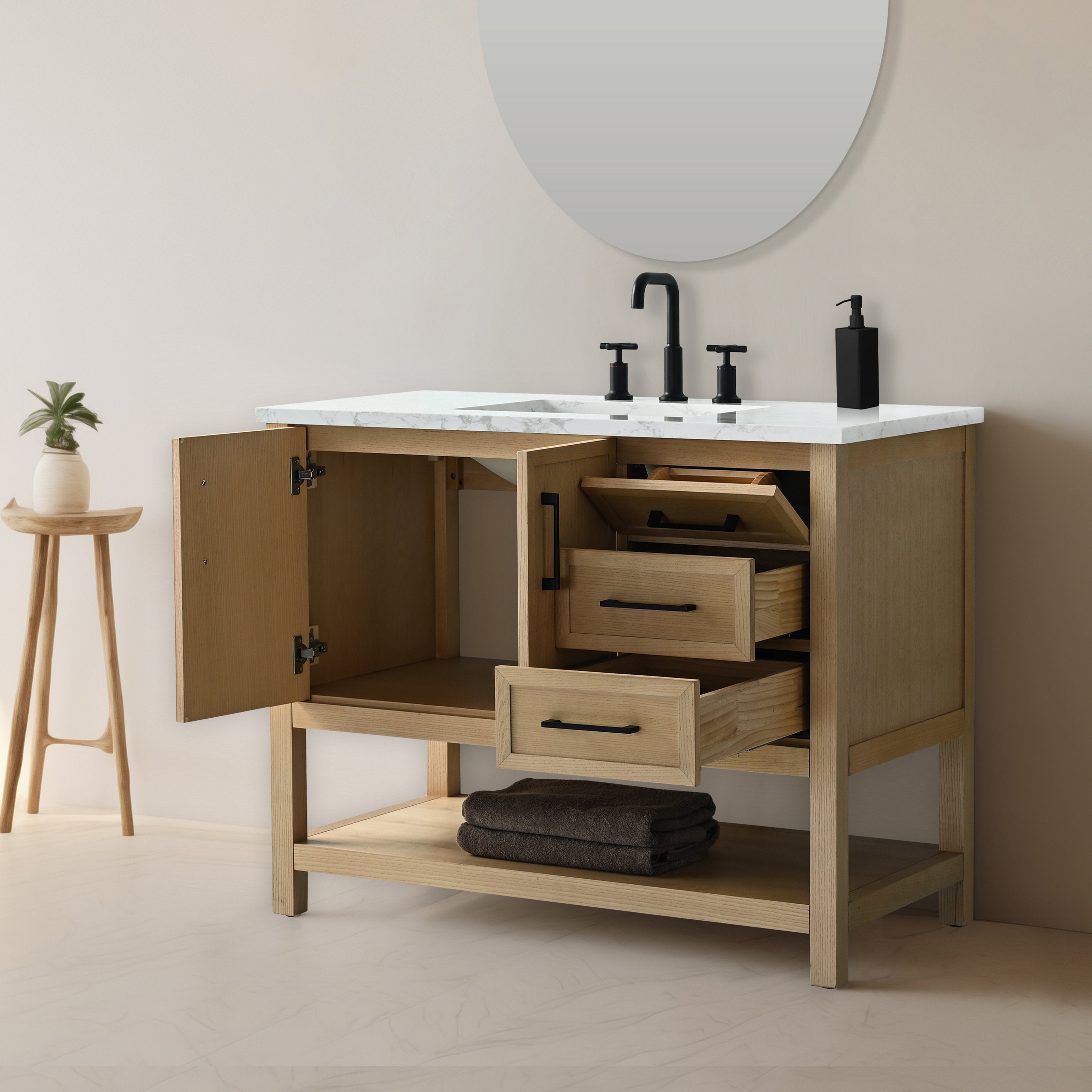 Freestanding 42-inch solid wood single-sink vanity with stone marble top, open cabinet door and two partially open drawers, black matte faucet and hardware, lower shelf with folded dark towels and round mirror above.