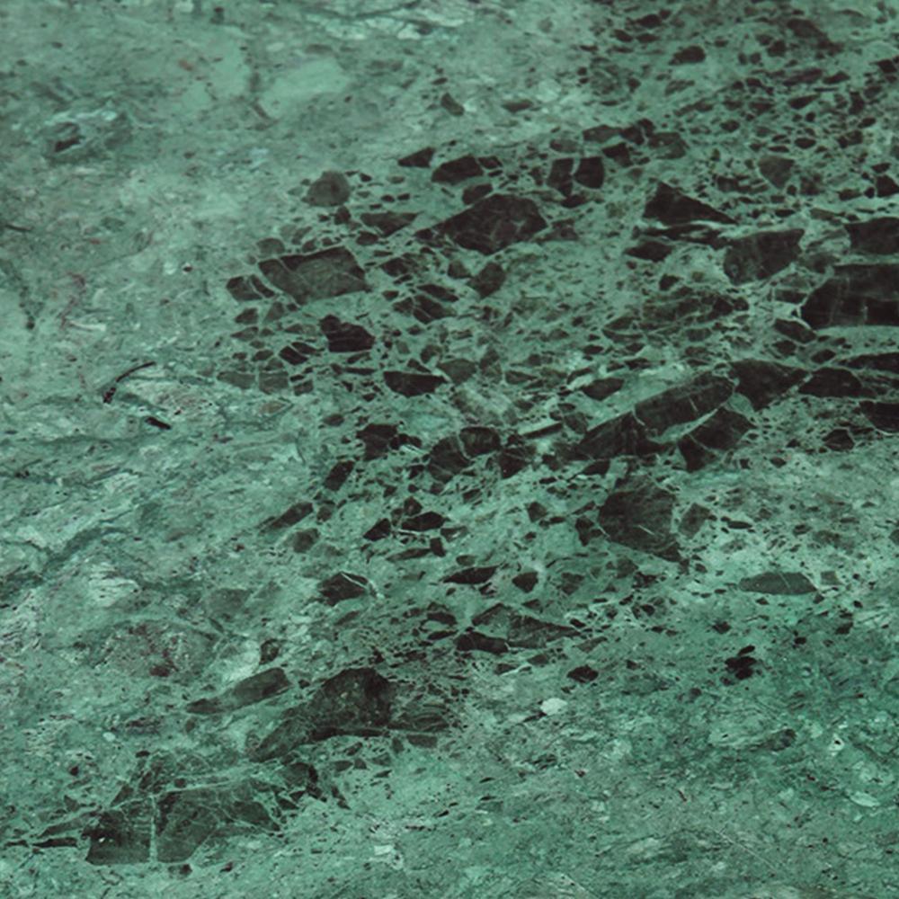 Close-up of a green marble tabletop with deep black veining and scattered stone fragments on a polished surface, highlighting the modern coffee table's natural stone texture.