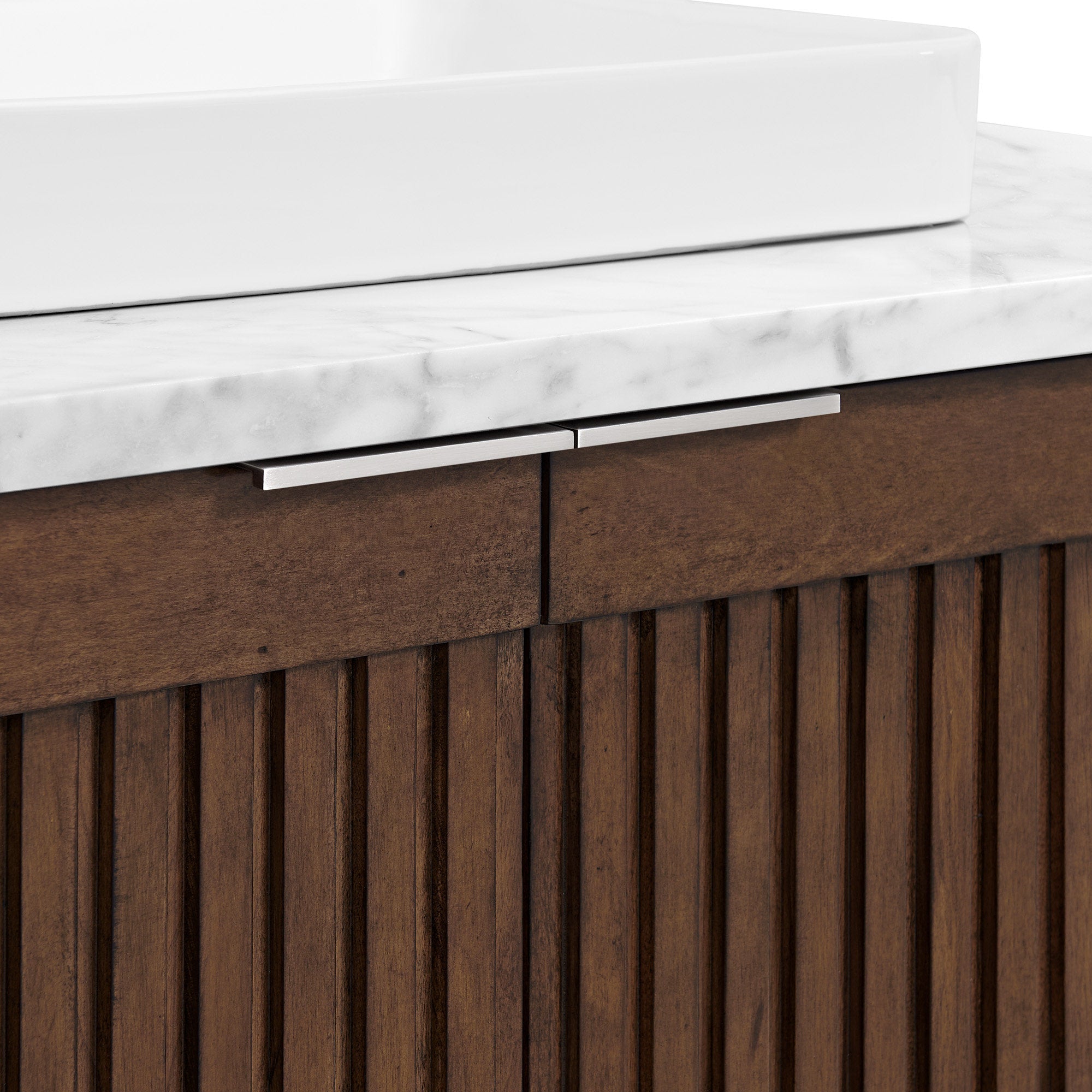 Close-up of a white ceramic vessel sink on a stone Calacatta marble top above a fluted natural wood vanity with vertical slats and slim brushed metal handles in a modern contemporary style.