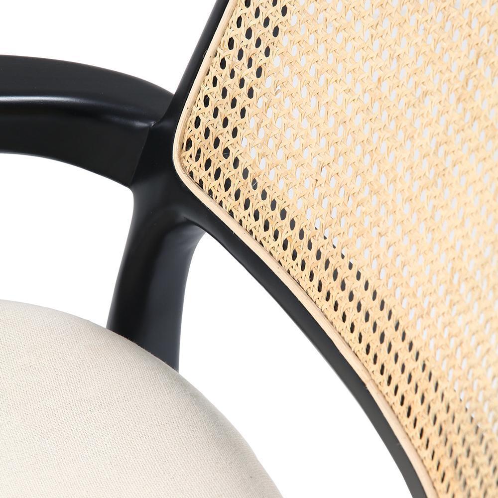 Close-up of a modern lounge chair showing a natural woven cane back panel set in a black wooden frame and the curved edge of a light beige upholstered seat cushion.