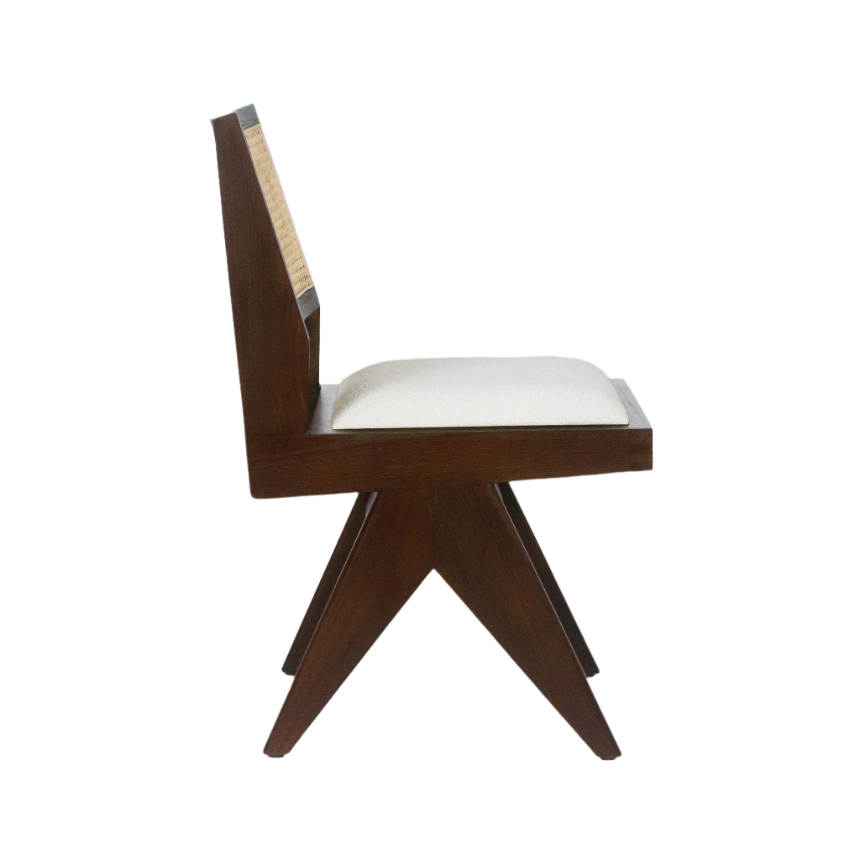 Side profile of an armless midcentury dining chair with a dark solid wood frame, woven cane back panel and cream upholstered seat resting on angled crossed legs.